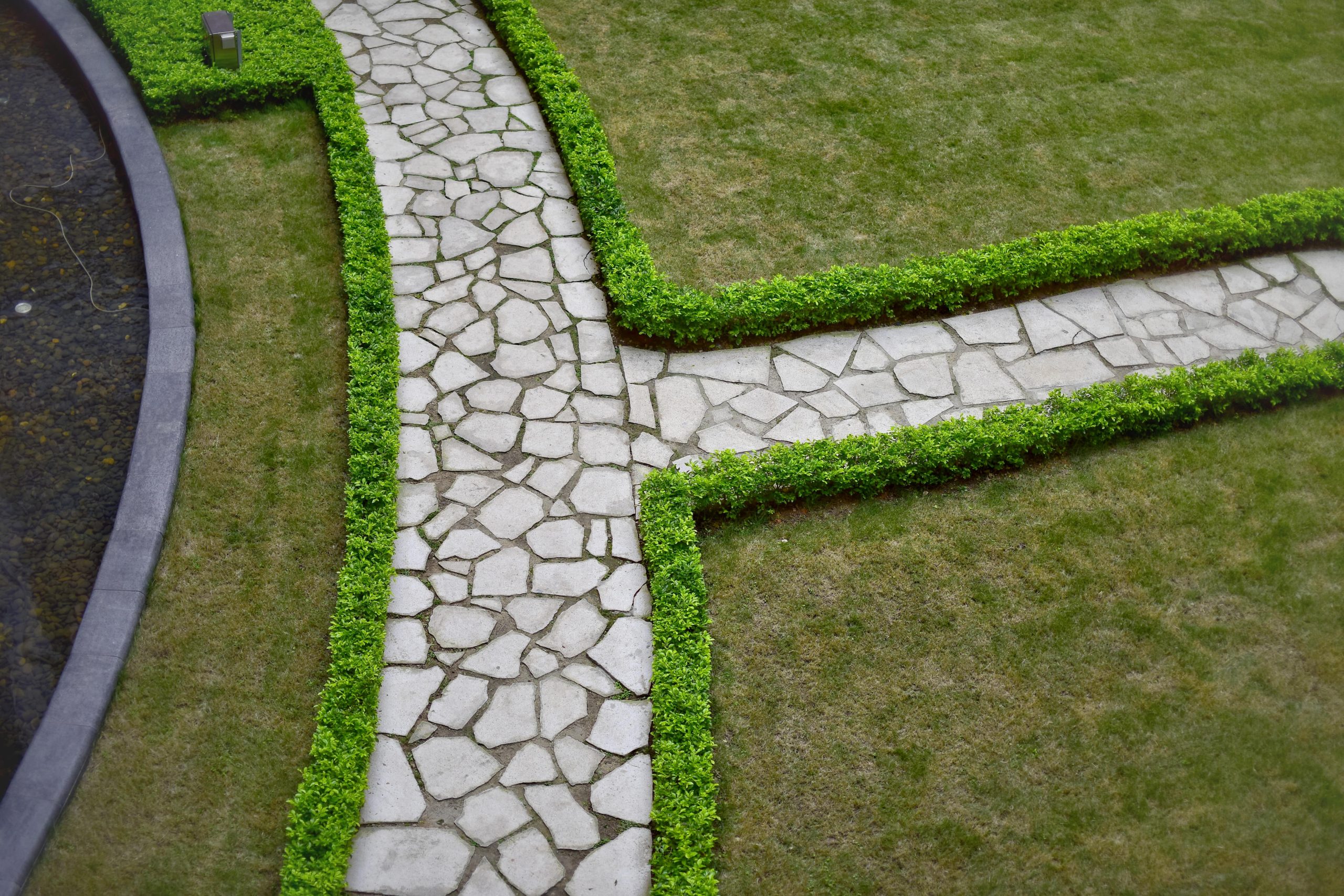 Stone garden pathway with green hedges in a landscaping design project in Cyprus.